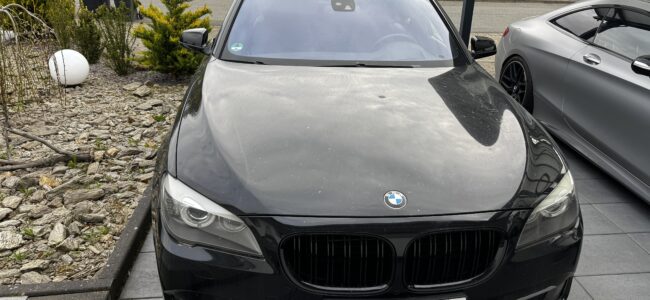 Hochwertiger BMW 750i in Schwarz, präsentiert sich vor einem Wohnhaus, ideal für anspruchsvolle Autofahrer, die Komfort und Stil suchen.
